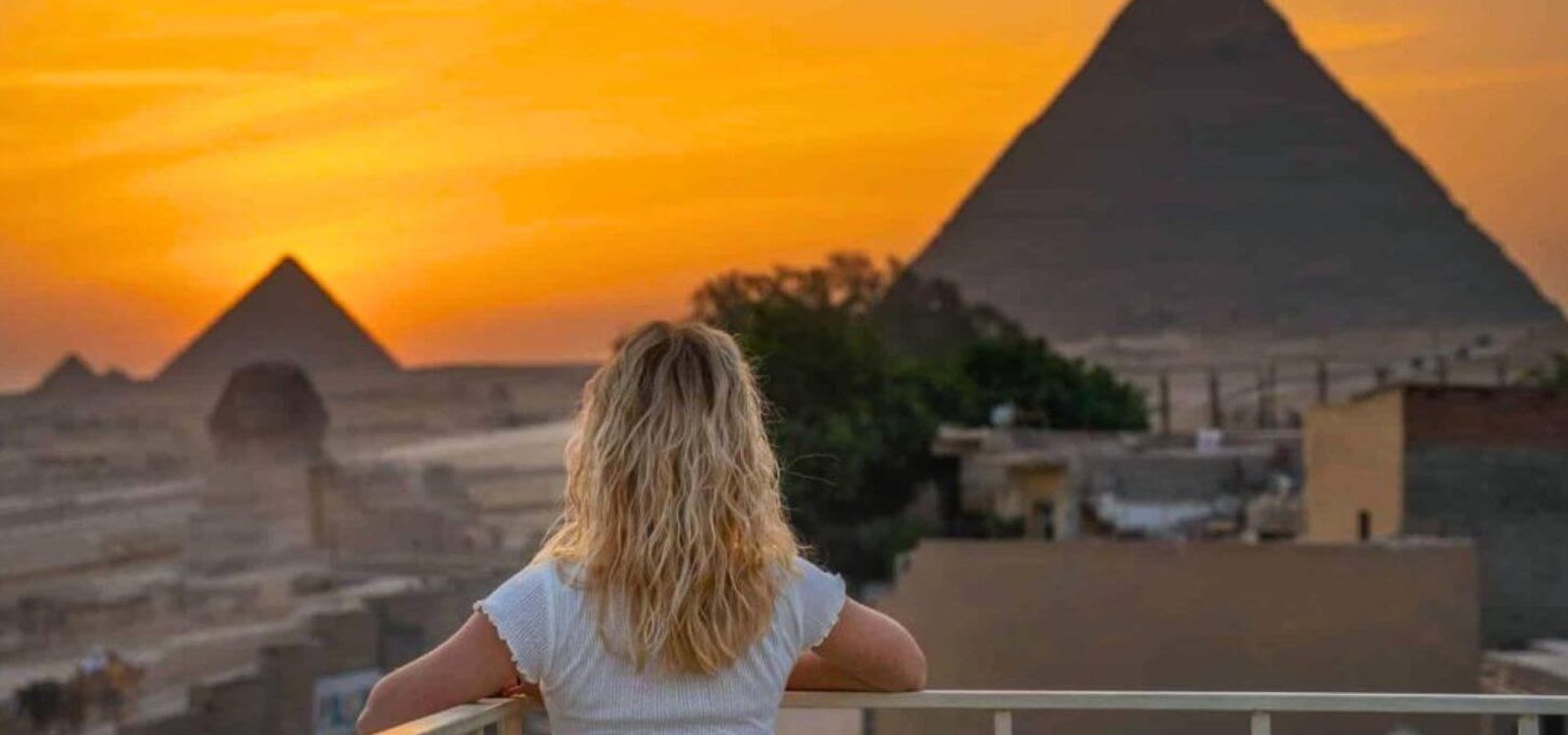 panoramic view of a woman stuns the pyramids of giza and the sphinx