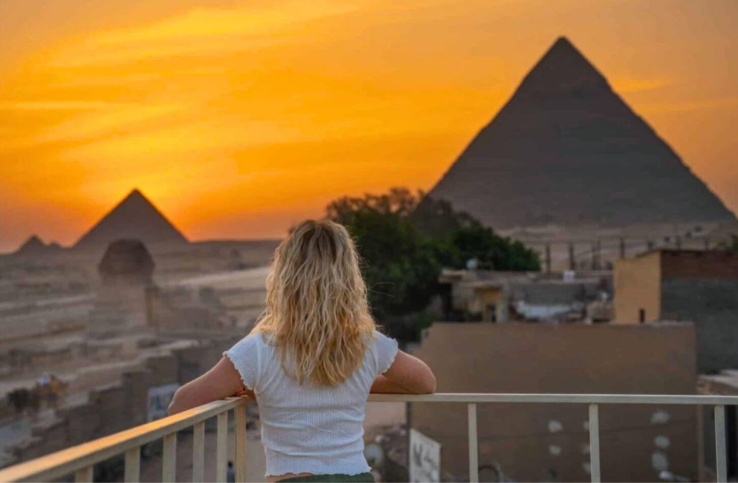 panoramic view of a woman stuns the pyramids of giza and the sphinx